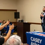 Casey Askar engaging with a diverse audience at a political town hall meeting.